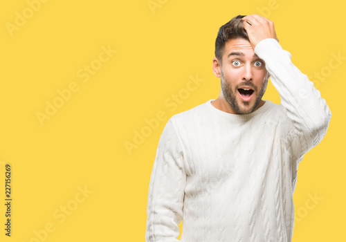 Young handsome man wearing winter sweater over isolated background surprised with hand on head for mistake, remember error. Forgot, bad memory concept.