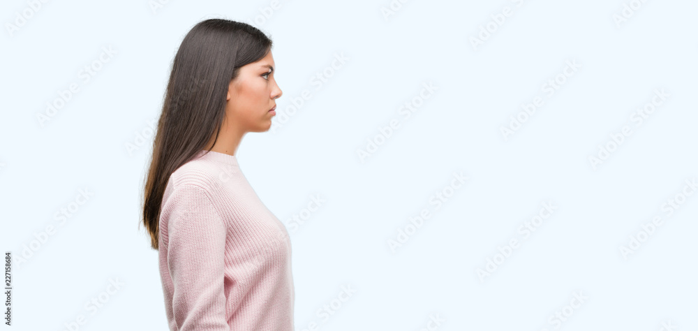 Young beautiful hispanic woman wearing a sweater looking to side, relax profile pose with natural face with confident smile. Young beautiful hispanic woman wearing a sweater looking to side, relax profile pose with natural face with confident smile.