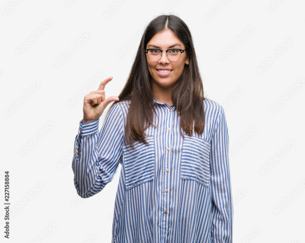 Young beautiful hispanic business woman smiling and confident gesturing with hand doing size sign with fingers while looking and the camera. Measure concept. Young beautiful hispanic business woman smiling and confident gesturing with hand doing size sign with fingers while looking and the camera. Measure concept.