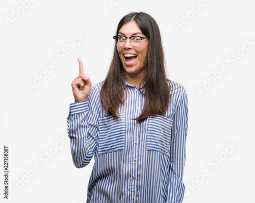 Young beautiful hispanic business woman pointing finger up with successful idea. Exited and happy. Number one.
