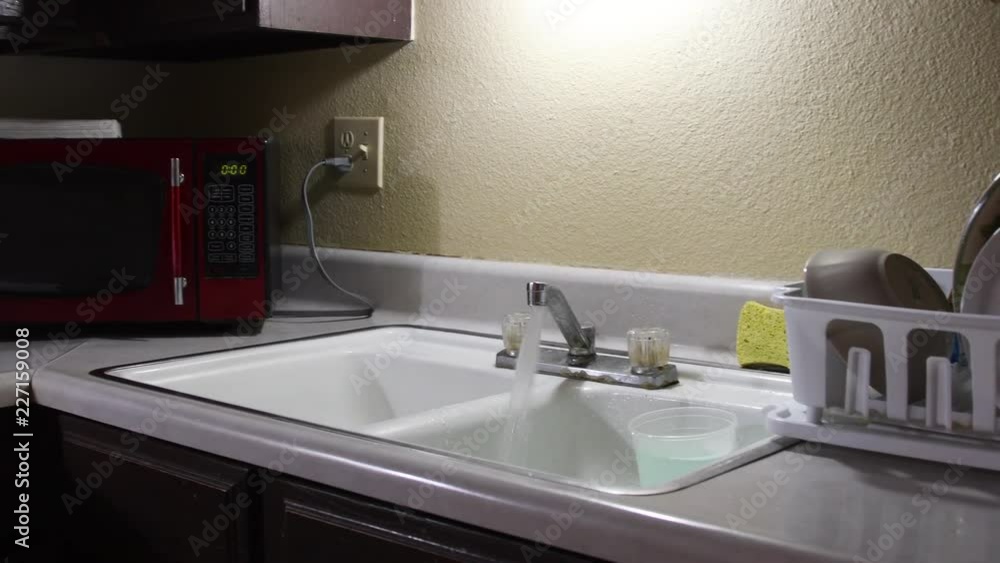 Water fills the 1980s porcelain style kitchen sink Stock ????????? Adobe Stock