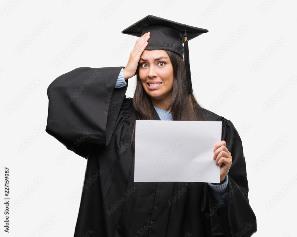 Young hispanic woman wearing graduated uniform holding diploma paper stressed with hand on head, shocked with shame and surprise face, angry and frustrated. Fear and upset for mistake. Young hispanic woman wearing graduated uniform holding diploma paper stressed with hand on head, shocked with shame and surprise face, angry and frustrated. Fear and upset for mistake.