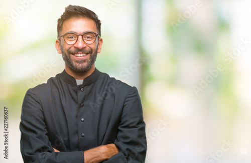 Canvastavla Adult hispanic catholic priest man over isolated background happy face smiling with crossed arms looking at the camera