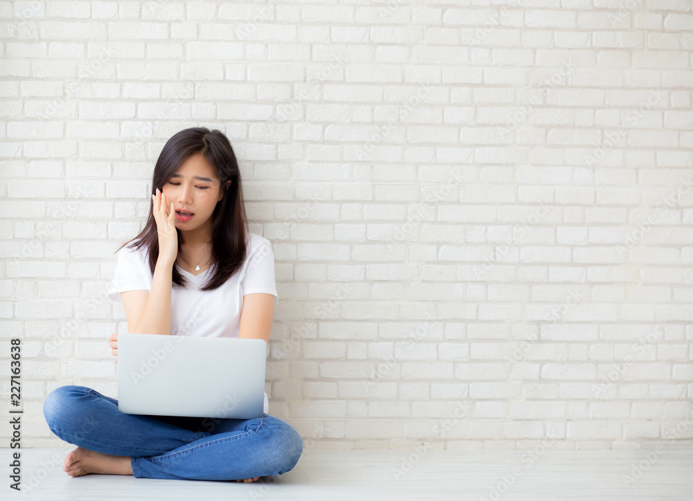 Beautiful of portrait asian young woman working online laptop and thinking and serious sitting on floor brick cement background, freelance girl using notebook computer, business and lifestyle concept. Beautiful of portrait asian young woman working online laptop and thinking and serious sitting on floor brick cement background, freelance girl using notebook computer, business and lifestyle concept.