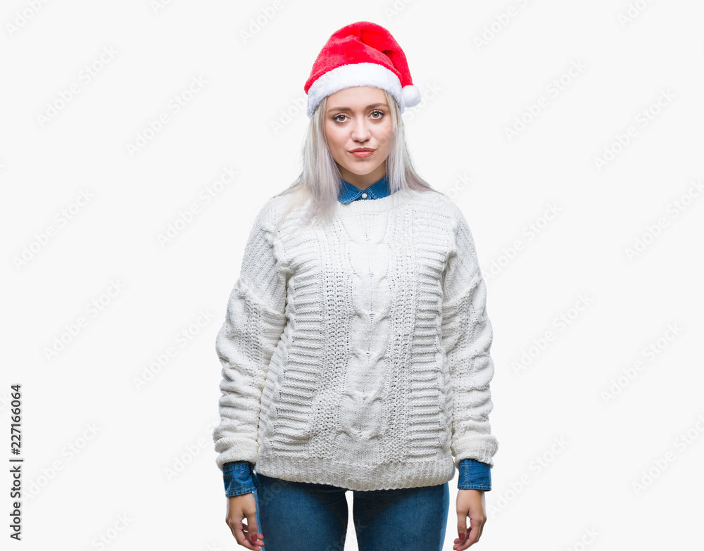 Young blonde woman wearing christmas hat over isolated background with serious expression on face. Simple and natural looking at the camera. Young blonde woman wearing christmas hat over isolated background with serious expression on face. Simple and natural looking at the camera.