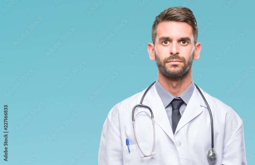 Young handsome doctor man over isolated background with serious expression on face. Simple and natural looking at the camera. Young handsome doctor man over isolated background with serious expression on face. Simple and natural looking at the camera.