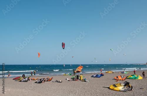 Many kitesurfer and windsurfer on ocean at surfer beach El Medano, Tenerife