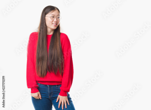 Young Chinese woman over isolated background wearing glasses looking away to side with smile on face, natural expression. Laughing confident.