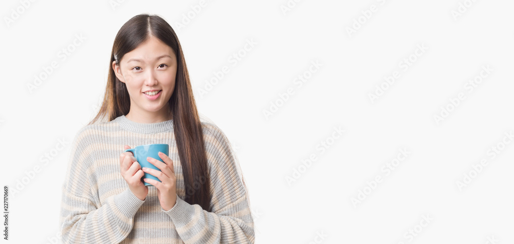 Young Chinese woman over isolated background driking cup of coffee with a happy face standing and smiling with a confident smile showing teeth Young Chinese woman over isolated background driking cup of coffee with a happy face standing and smiling with a confident smile showing teeth