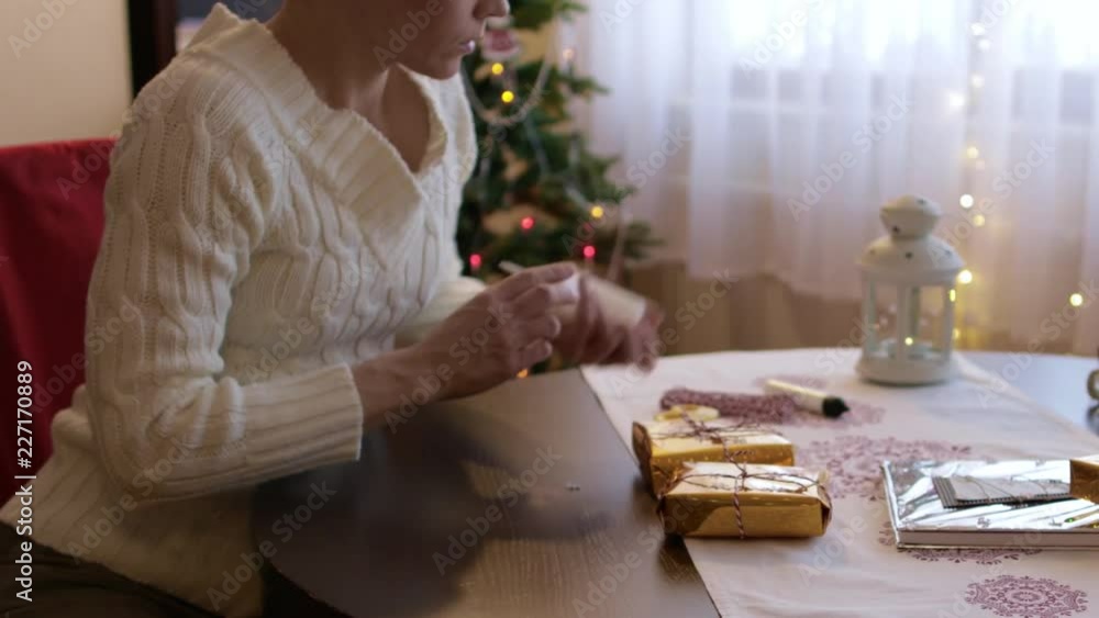 Young lady between 30 and 35 years old prepares Christmas gifts for her relatives Young lady between 30 and 35 years old prepares Christmas gifts for her relatives