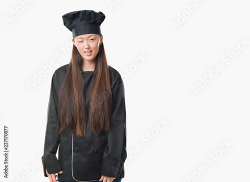 Young Chinese woman over isolated background wearing chef uniform winking looking at the camera with sexy expression, cheerful and happy face.