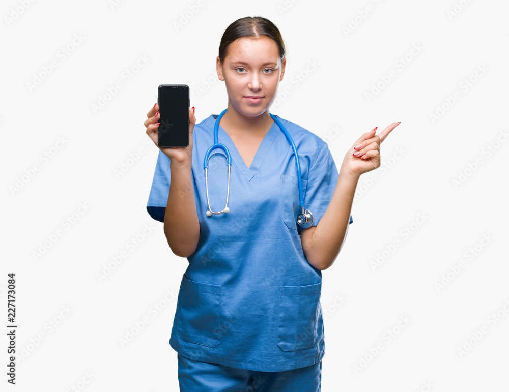 Young caucasian doctor woman showing smarpthone over isolated background very happy pointing with hand and finger to the side Young caucasian doctor woman showing smarpthone over isolated background very happy pointing with hand and finger to the side