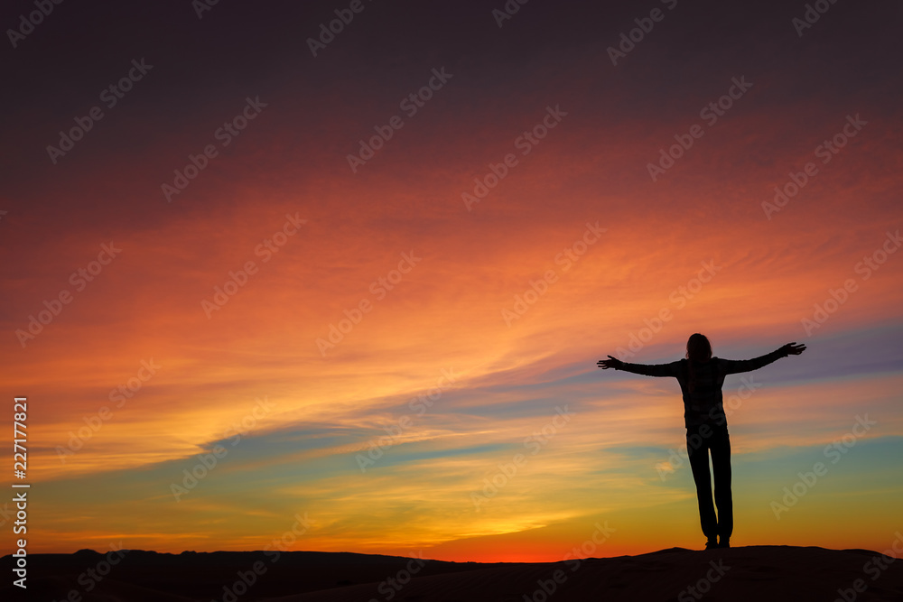 Silhouette of woman posing on sand dune during the sunset