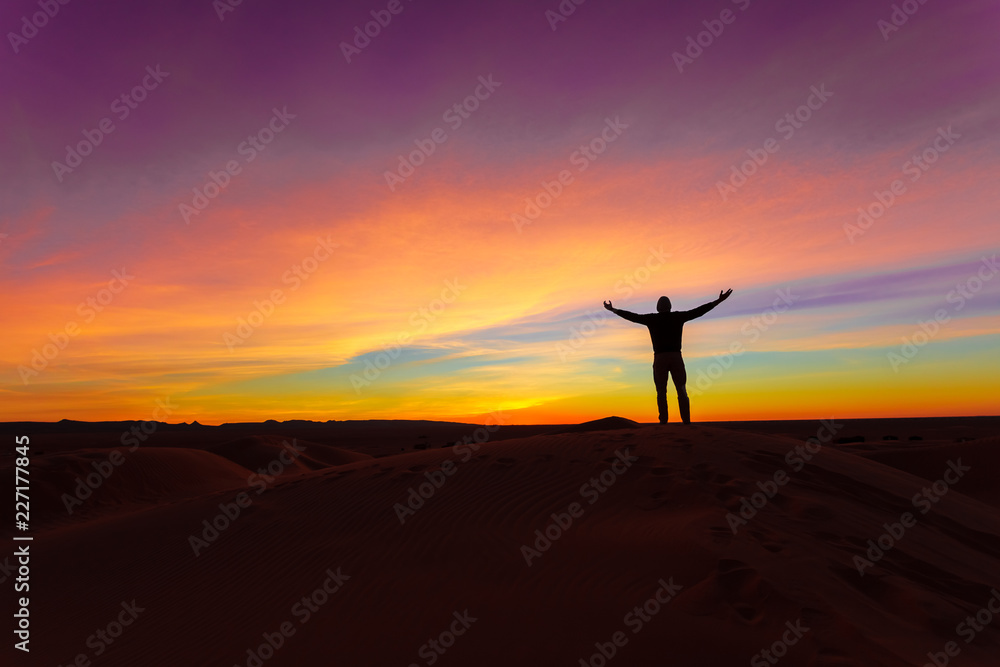 Silhouette of man posing on sand dune during the sunset Silhouette of man posing on sand dune during the sunset
