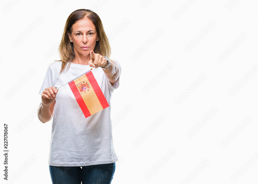 Middle age hispanic woman holding flag of Spain over isolated background pointing with finger to the camera and to you, hand sign, positive and confident gesture from the front Middle age hispanic woman holding flag of Spain over isolated background pointing with finger to the camera and to you, hand sign, positive and confident gesture from the front