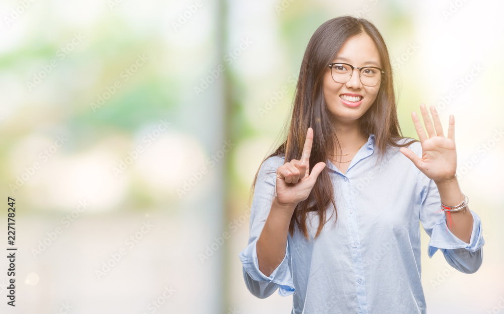 Young asian business woman wearing glasses over isolated background showing and pointing up with fingers number seven while smiling confident and happy. Young asian business woman wearing glasses over isolated background showing and pointing up with fingers number seven while smiling confident and happy.