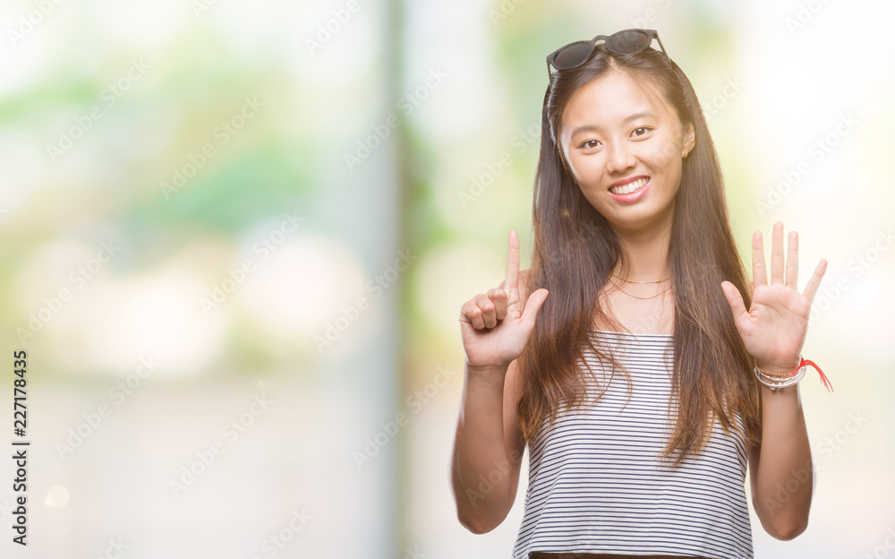 Young asian woman wearing sunglasses over isolated background showing and pointing up with fingers number seven while smiling confident and happy. Young asian woman wearing sunglasses over isolated background showing and pointing up with fingers number seven while smiling confident and happy.