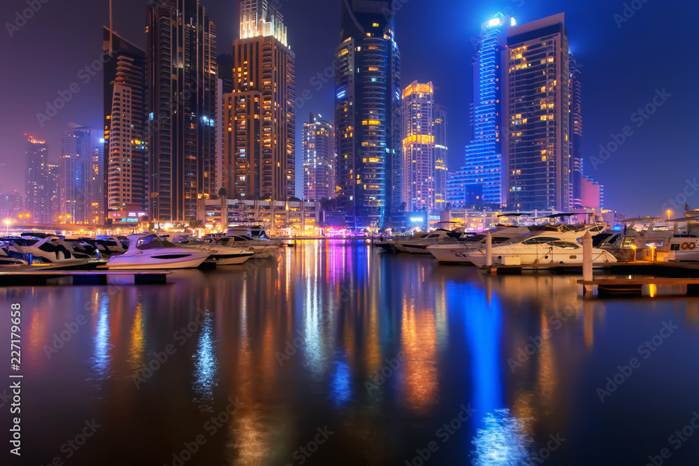Beautiful view to Dubai Marina, UAE. Luxury yachts at pier. Long exposure time lapse effect at night
