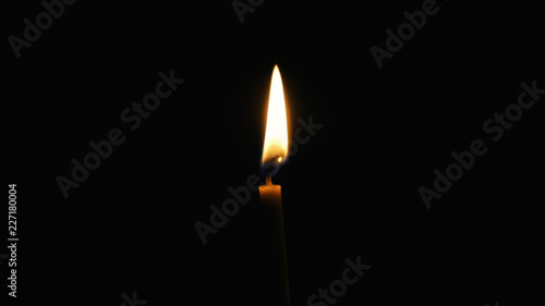 Flame on the wax candle burns and shines in the Orthodox ancient dark temple