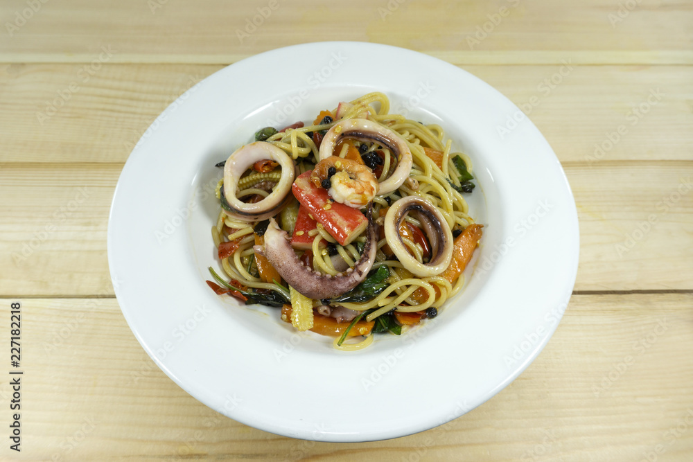 Spaghetti seafood in a white dish on a wood floor table,Top view copy space.. Spaghetti seafood in a white dish on a wood floor table,Top view copy space..