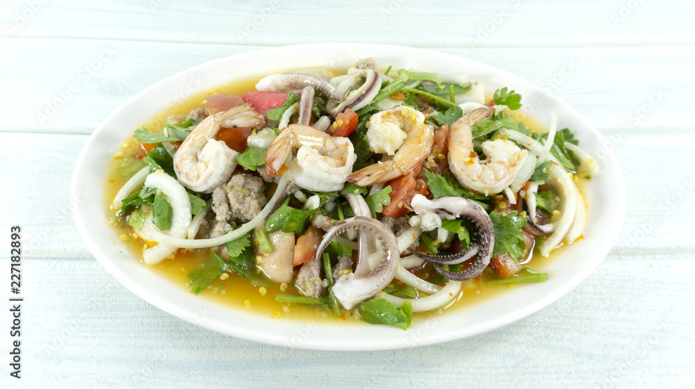 spicy seafood shrimp and squid salad in white plate Thai foods. white wooden backdrop. Top view. Copy Space. spicy seafood shrimp and squid salad in white plate Thai foods. white wooden backdrop. Top view. Copy Space.