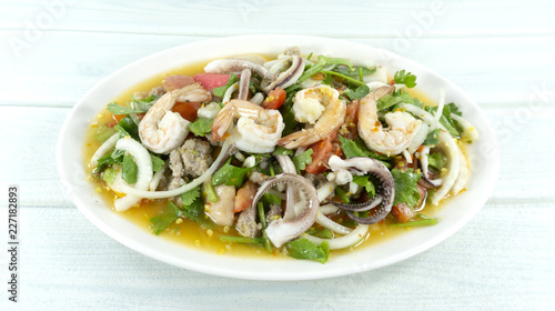 spicy seafood shrimp and squid salad in white plate Thai foods. white wooden backdrop. Top view. Copy Space.