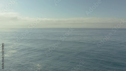 Aerial low decend pullback over the sand on the beach over rocks crashing on the water photo