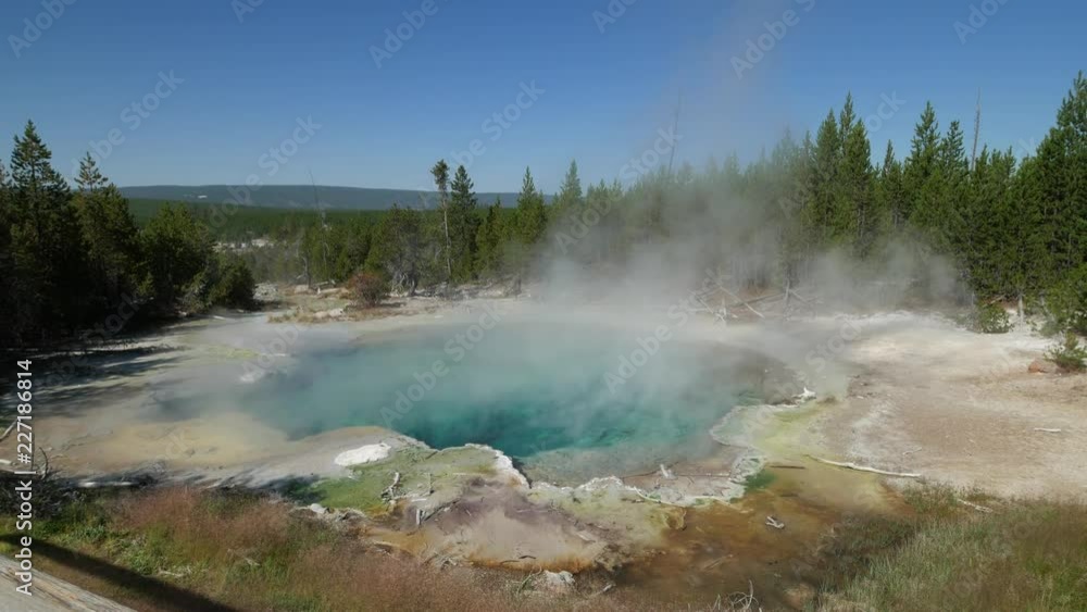 Scenic wide shot of the blue Emerald Spring with steam rising up at the Norris Geyser Basin at Yellowstone National Park in Wyoming. Scenic wide shot of the blue Emerald Spring with steam rising up at the Norris Geyser Basin at Yellowstone National Park in Wyoming.