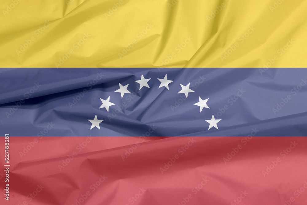 Fabric flag of Venezuela. Crease of Venezuelan flag background, yellow blue and red with an arc of eight white stars centered on the blue band. Fabric flag of Venezuela. Crease of Venezuelan flag background, yellow blue and red with an arc of eight white stars centered on the blue band.