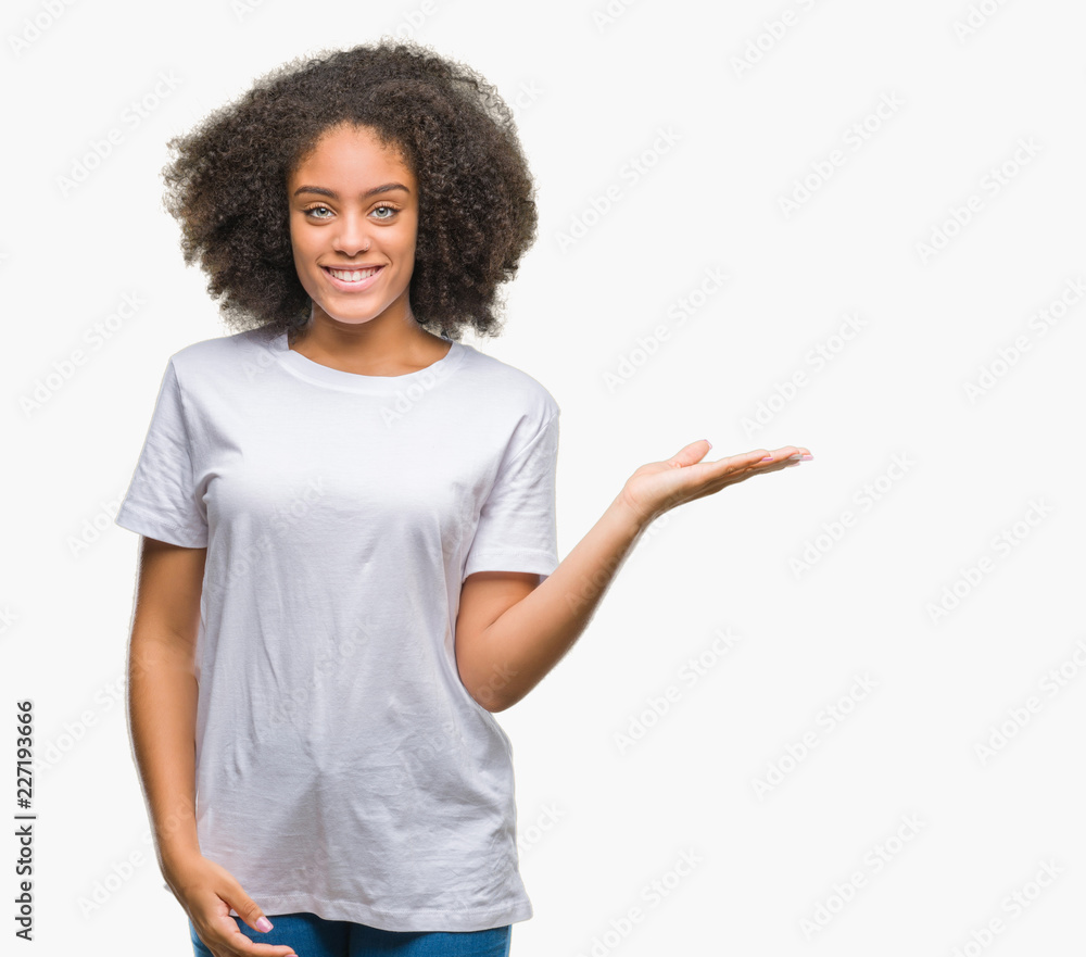 Young afro american woman over isolated background smiling cheerful presenting and pointing with palm of hand looking at the camera. Young afro american woman over isolated background smiling cheerful presenting and pointing with palm of hand looking at the camera.