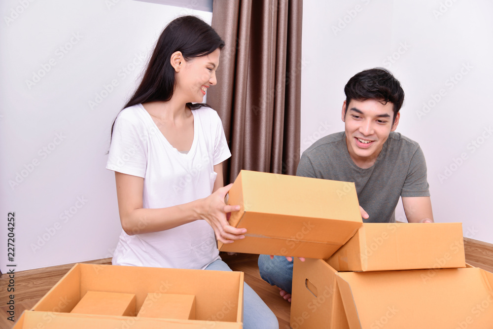Moving house Concept. Asian young man is carrying his belongings. Young Asian women are holding their stuff in a paper box. Young are happy in the new house. Moving house Concept. Asian young man is carrying his belongings. Young Asian women are holding their stuff in a paper box. Young are happy in the new house.