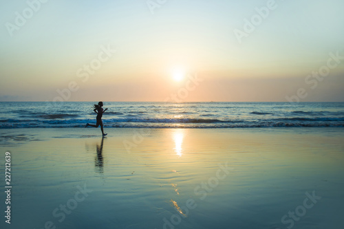 silhouette of young happy and attractive African American runner woman exercising in running fitness workout at beautiful beach jogging and enjoying sunset