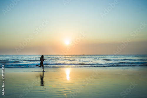 silhouette of young happy and attractive African American runner woman exercising in running fitness workout at beautiful beach jogging and enjoying sunset