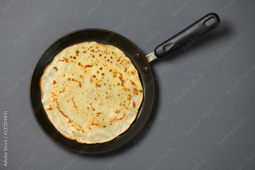 Crepe closeup, thin pancake on a frying pan, grey background