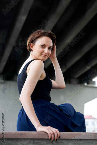 young girl posing under the bridge, dressed in black, modern architecture