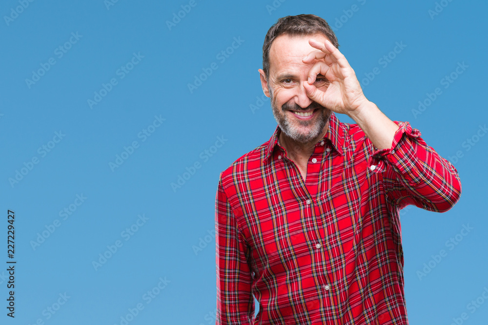 Fototapeta premium Middle age hoary senior man over isolated background doing ok gesture with hand smiling, eye looking through fingers with happy face.