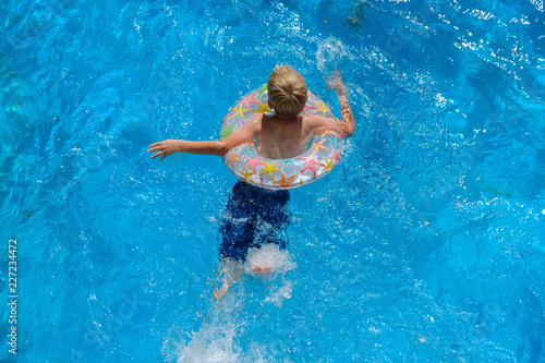 Boy floating on an inflatable circle in the pool, top view photo