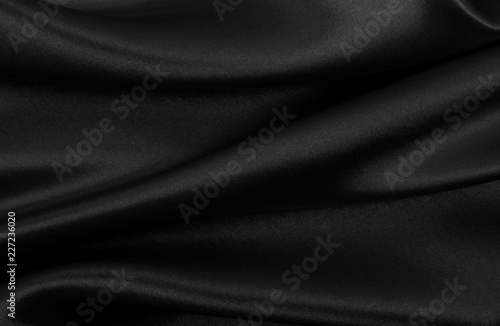 Smooth elegant black silk or satin texture as abstract background. Luxurious background design