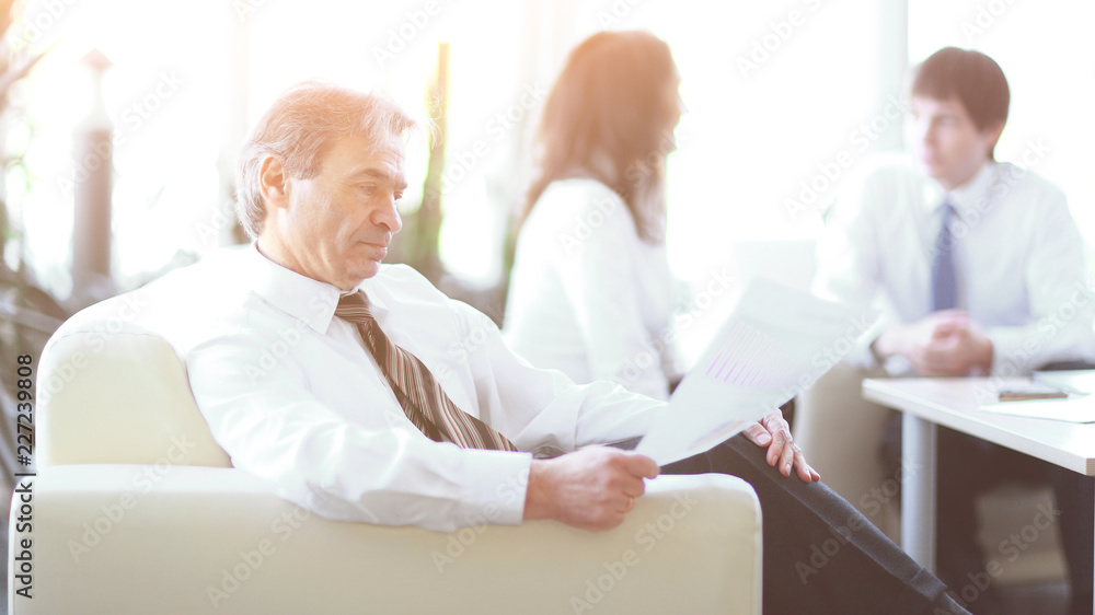 businessman pondering a document sitting in a modern office businessman pondering a document sitting in a modern office