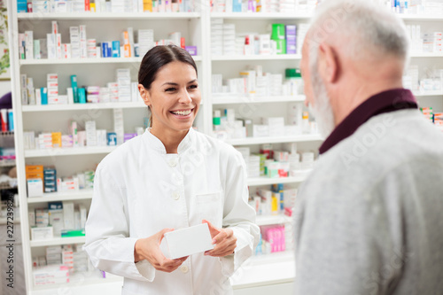 Medicine, pharmaceutics, health care and people concept - Happy female pharmacist giving medications to senior male customer photo