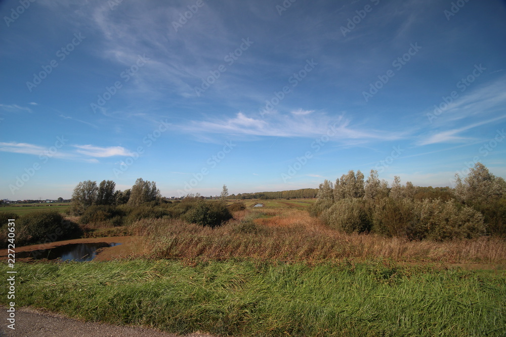 Blue sky with cirrus clouds above the meadows at the dyke along river Hollandsche IJssel in Nieuwerkerk aan den IJssel in the Netherlands. Blue sky with cirrus clouds above the meadows at the dyke along river Hollandsche IJssel in Nieuwerkerk aan den IJssel in the Netherlands.
