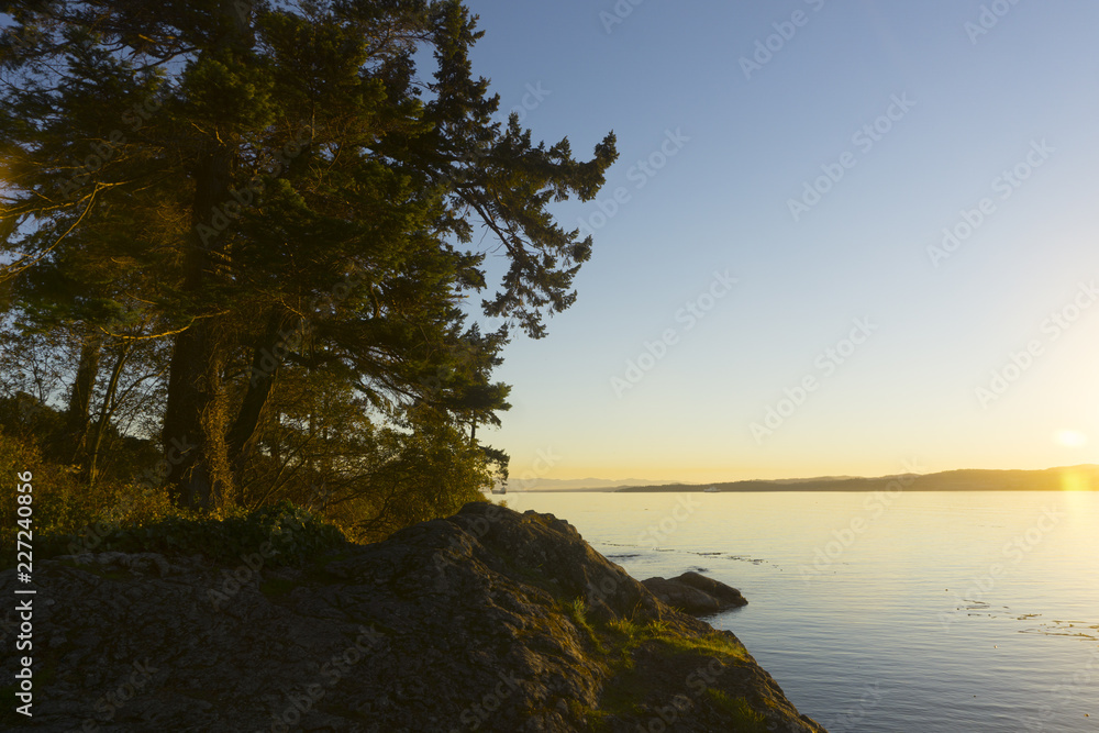 Island sunset. Sunset over water with rocky island and trees