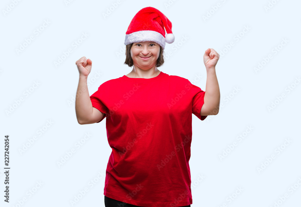 Young adult woman with down syndrome wearing christmas hat over isolated background celebrating mad and crazy for success with arms raised and closed eyes screaming excited. Winner concept Young adult woman with down syndrome wearing christmas hat over isolated background celebrating mad and crazy for success with arms raised and closed eyes screaming excited. Winner concept
