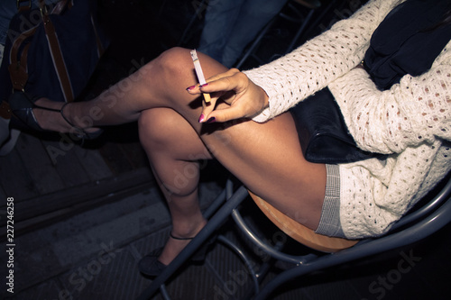 fashion girl smoking a cigarette, young model smokes tobacco sitting on a chair (top view)
