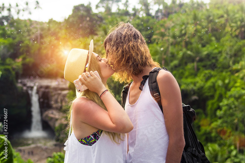 Young honeymoon couple in the jungle kissing on the watefall background. Bali island.