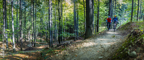 Mountain biking women and man riding on bikes in early spring mountains forest landscape. Couple cycling MTB enduro flow trail track. Outdoor sport activity. photo