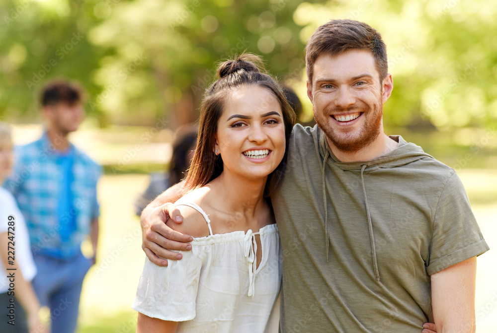 people and relationships concept - happy couple hugging at summer park people and relationships concept - happy couple hugging at summer park