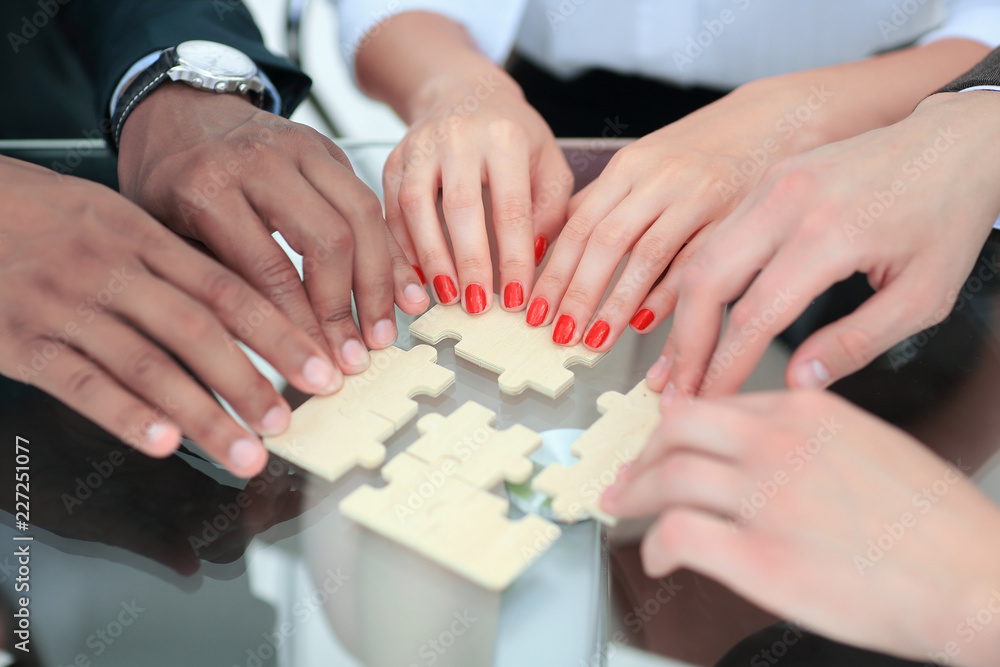 closeup. business team with puzzle pieces behind a Desk closeup. business team with puzzle pieces behind a Desk