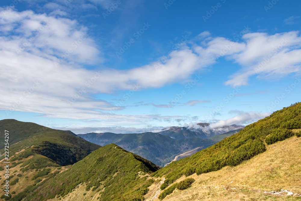 Autumn mountain ridge under blue sky with white clouds