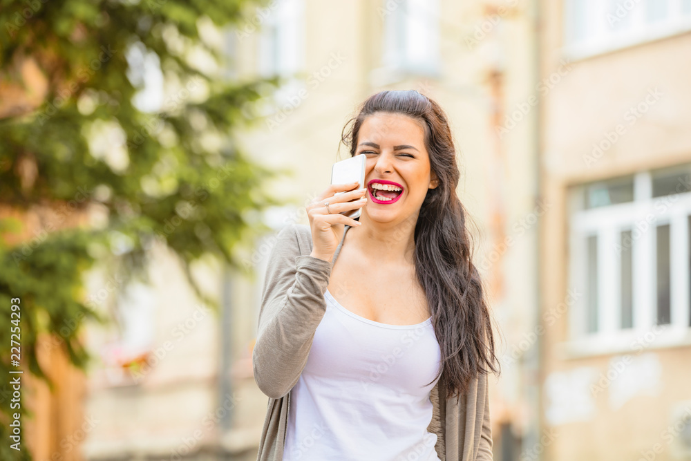 Cute young woman using cellphone in urban surroundings. Cute young woman using cellphone in urban surroundings.